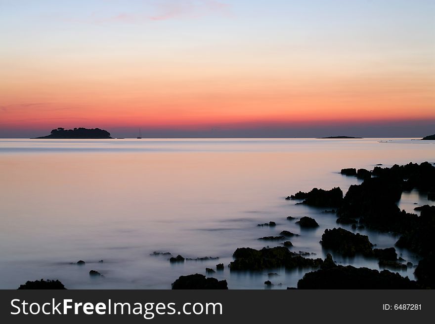 Sunset on a rocky beach with view onto an island