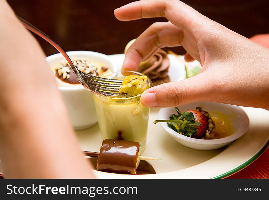 Woman scooping her dessert from a cup on a plate with folk. Woman scooping her dessert from a cup on a plate with folk