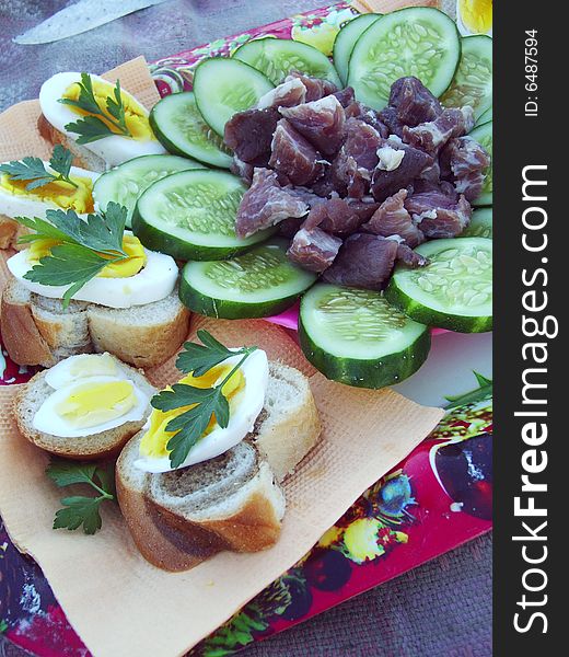Meal for a picnic: eggs, cucumbers, meat, bread