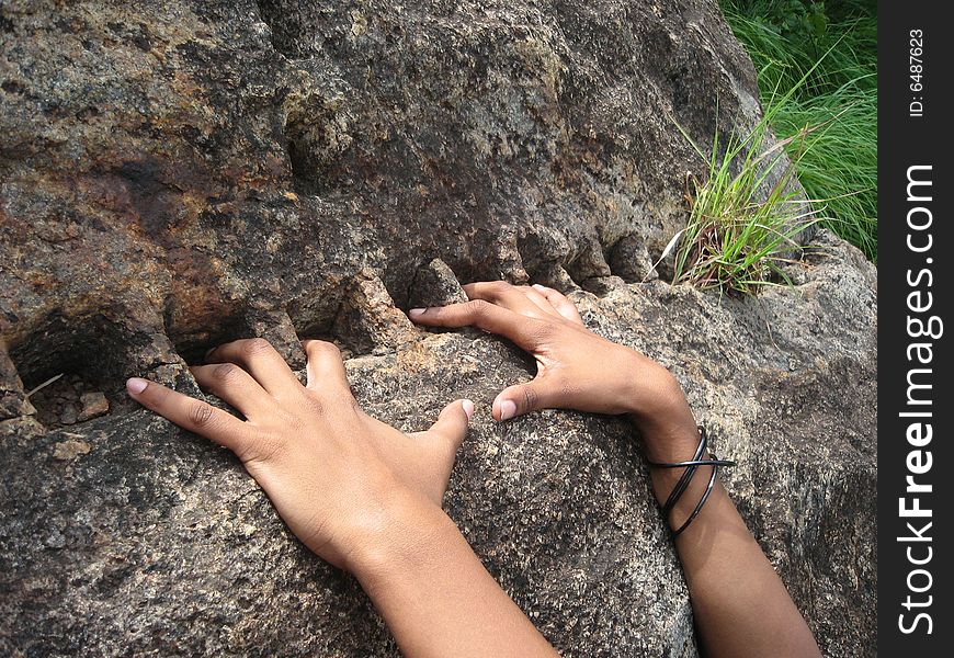 Square pieces have been carved on d rock. The stretched fingers of a teenager just show the youthful exuberance. Square pieces have been carved on d rock. The stretched fingers of a teenager just show the youthful exuberance