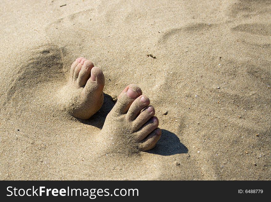 The fingers of feet which are sticking out of sand