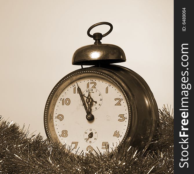 Old Alarm Clock showing few minutes to twelve sepia tone