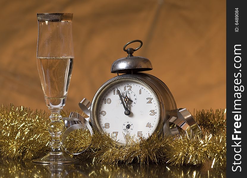 Old Alarm Clock showing few minutes to twelve with glass of champagne