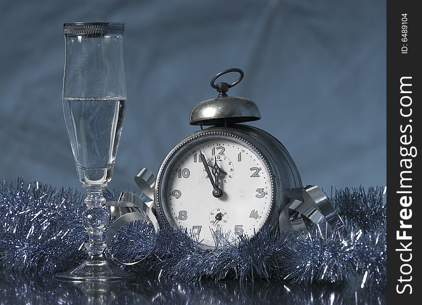 Old Alarm Clock showing few minutes to twelve with glass of champagne