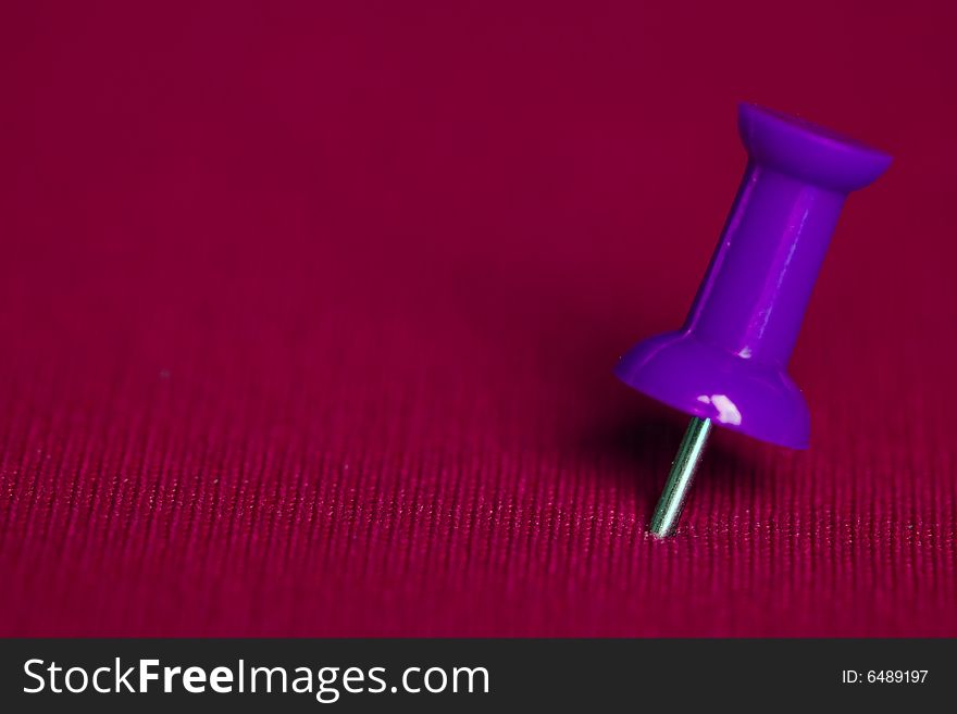 Close up of purple push pin on pink background. Close up of purple push pin on pink background