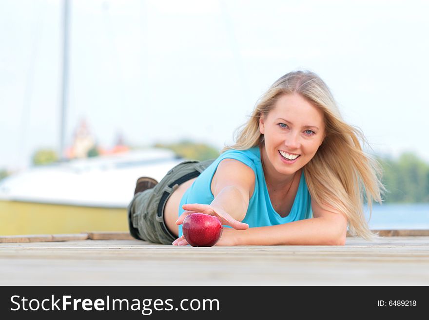 The girl overlies the foot-bridge and reaches for the apple. The girl overlies the foot-bridge and reaches for the apple