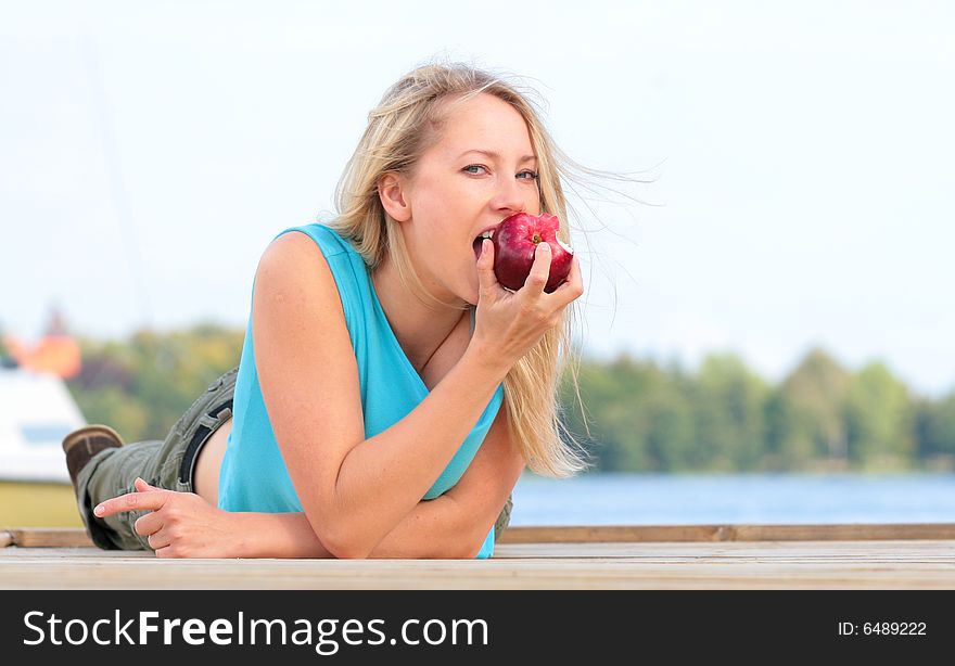 The girl overlies the foot-bridge and reaches for the apple. The girl overlies the foot-bridge and reaches for the apple