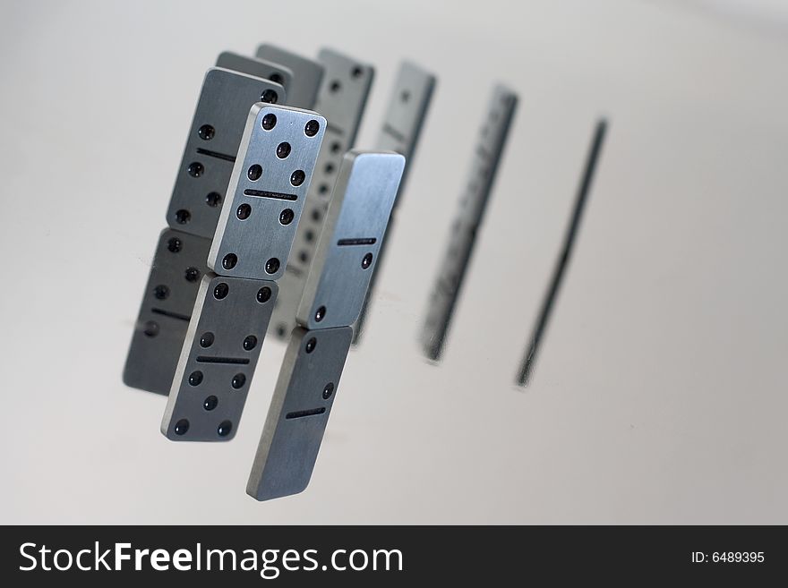 Steel dominoes in a row with reflection in polished surface