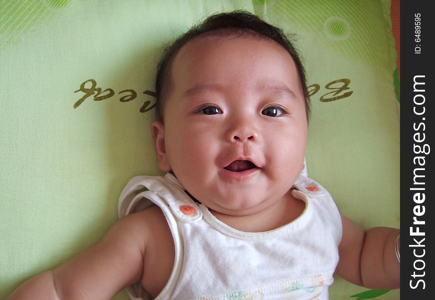 Laughing baby with her mouth opening on a pillow. Laughing baby with her mouth opening on a pillow