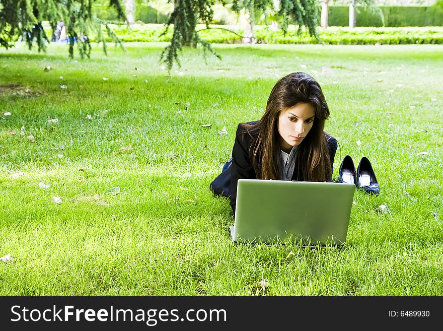 Young happy businesswoman working on the grass. Young happy businesswoman working on the grass