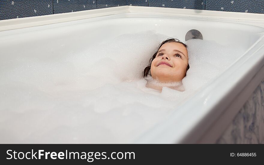 Little smiling girl lying in a bathtub closeup. Little smiling girl lying in a bathtub closeup