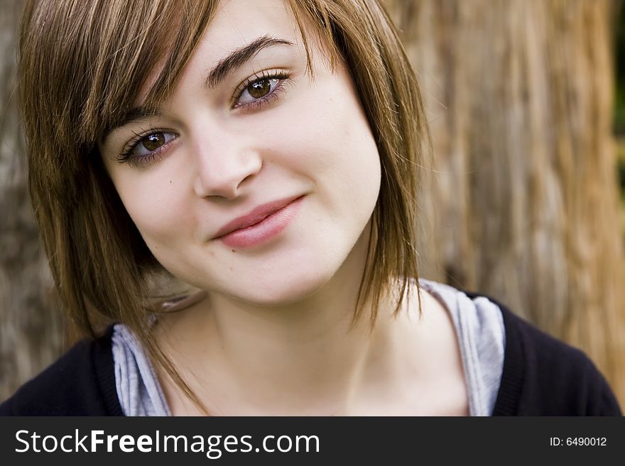 Young woman close portrait with tree trunk as background