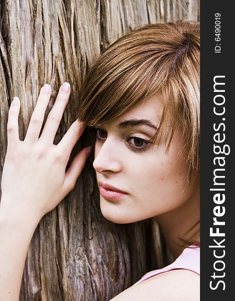 Young woman portrait over a tree trunk