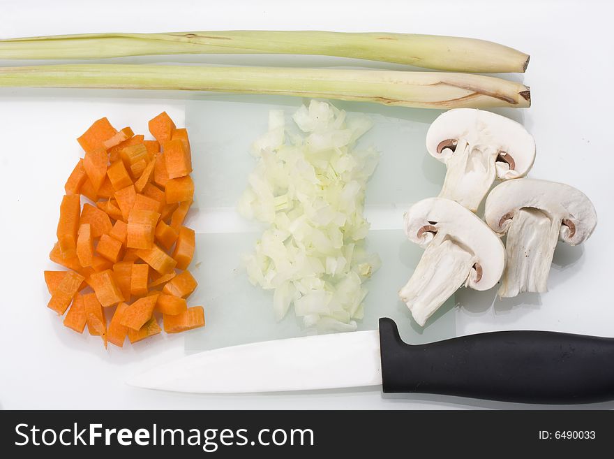 Sliced carrots, onions and champignons on a glass chopping board. Sliced carrots, onions and champignons on a glass chopping board