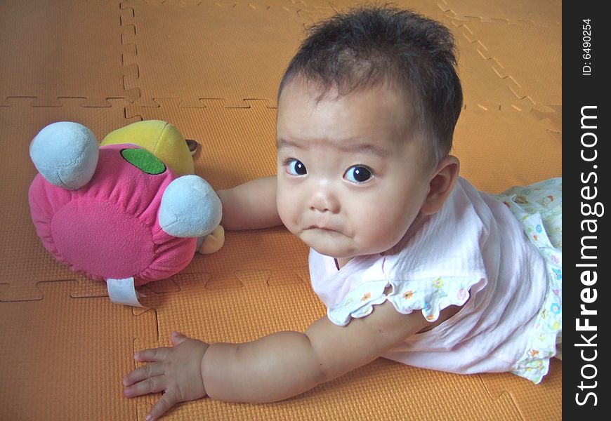 Lovely big eyes baby and toy on a yellow mat. Lovely big eyes baby and toy on a yellow mat
