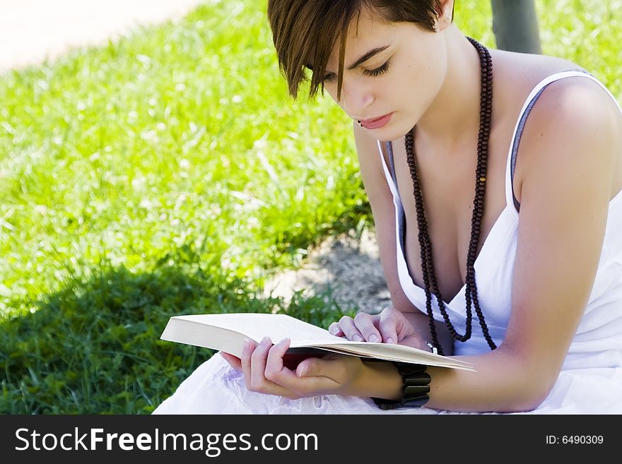 Beautiful blond woman reading over the grass