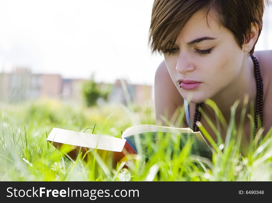 Young beautiful blonde reading over the grass. Young beautiful blonde reading over the grass