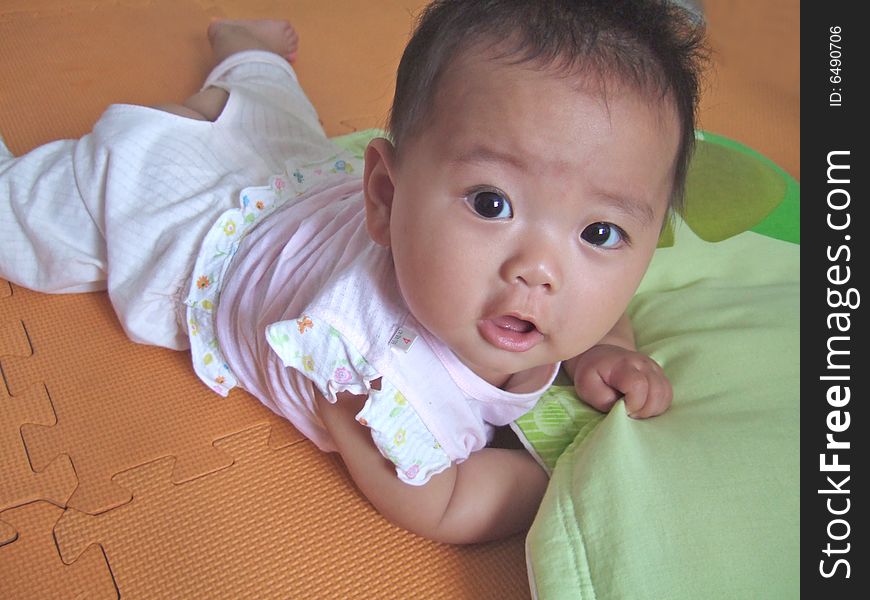 Lovely big eyes baby on a yellow mat. Lovely big eyes baby on a yellow mat