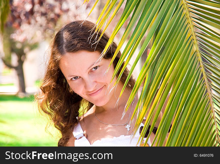 Joyful girl behind a palm branch, Valencia, Spain