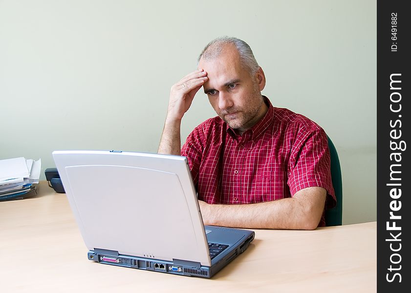 Thoughtful office worker working at the desk with laptop