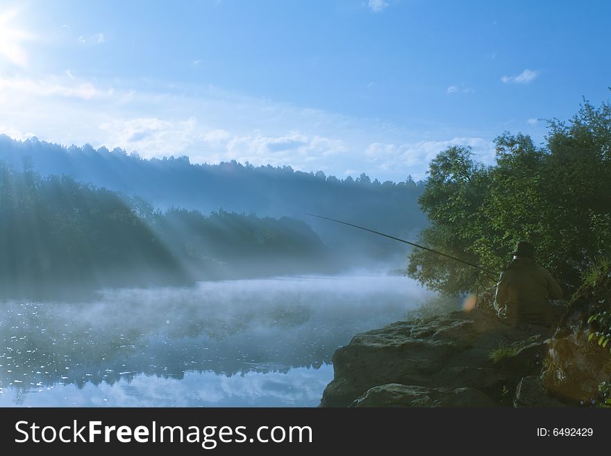 Morning landscape of misty river with sunlight rays and lonely fisherman. Morning landscape of misty river with sunlight rays and lonely fisherman