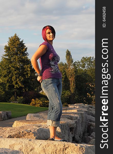 An red hair girl in jeans standing on the shore of lake Ontario at sunset. An red hair girl in jeans standing on the shore of lake Ontario at sunset.