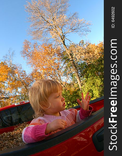 A young girl stands in the back of a pick-up truck filled with leaves while the trees in the background show their fall colors. A young girl stands in the back of a pick-up truck filled with leaves while the trees in the background show their fall colors.