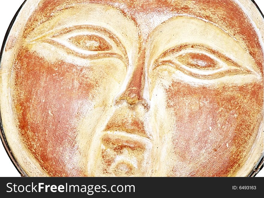 A terra-cotta wall hanging of a facial expression. A terra-cotta wall hanging of a facial expression.