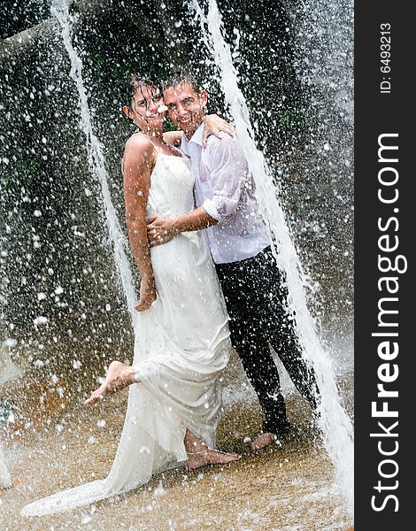 Bride and groom dancing under a water fountain on their wedding day. Bride and groom dancing under a water fountain on their wedding day.