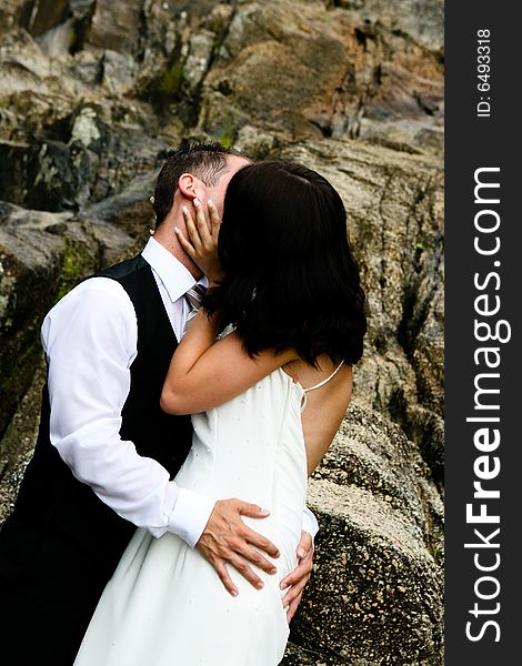 Happy bride and groom kissing on top of a mountain. Happy bride and groom kissing on top of a mountain.