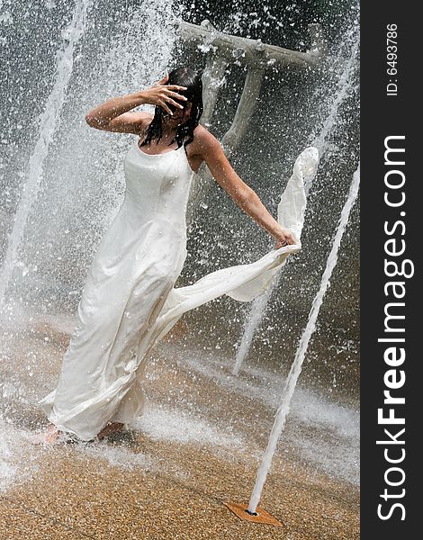 Beautiful young bride playing in a waterfall on her wedding day. Beautiful young bride playing in a waterfall on her wedding day.