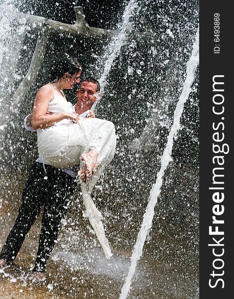 Bride and groom dancing under a water fountain on their wedding day. Bride and groom dancing under a water fountain on their wedding day.