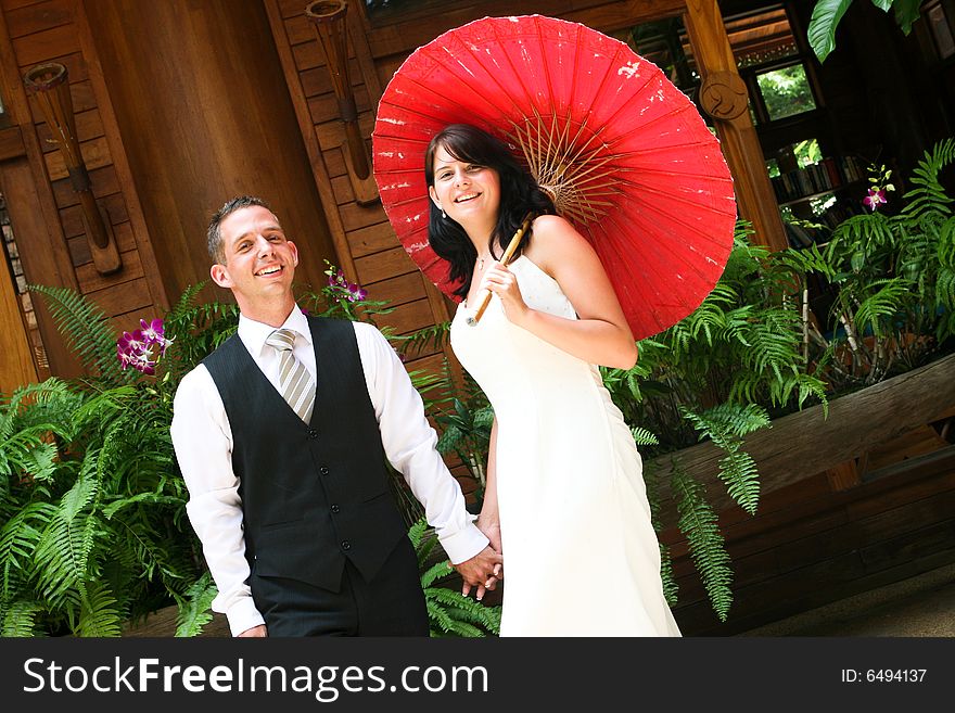 Groom with his bride carrying a red Asian umbrella. Groom with his bride carrying a red Asian umbrella.