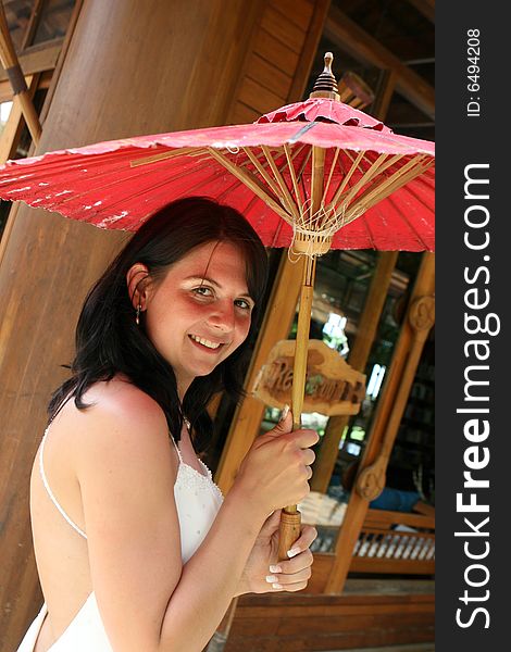 Portrait of a beautiful brunette bride with a red parasol. Portrait of a beautiful brunette bride with a red parasol.