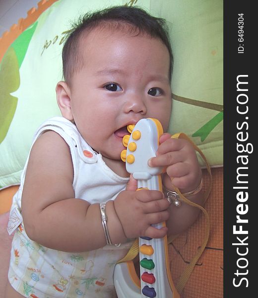 Happy baby and toy on a green pillow