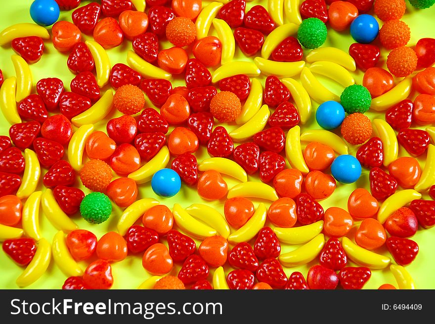 Colorful fruit candy on yellow background