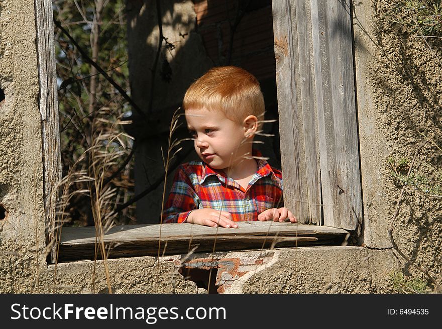 A three-and-a-half year old boy looks out of a window of an abandoned, single-room schoolhouse. A three-and-a-half year old boy looks out of a window of an abandoned, single-room schoolhouse.