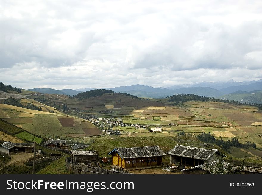 Small village in Yunnan province, near Shangrila town in China. Simple wooden houses and rice fields. Small village in Yunnan province, near Shangrila town in China. Simple wooden houses and rice fields.
