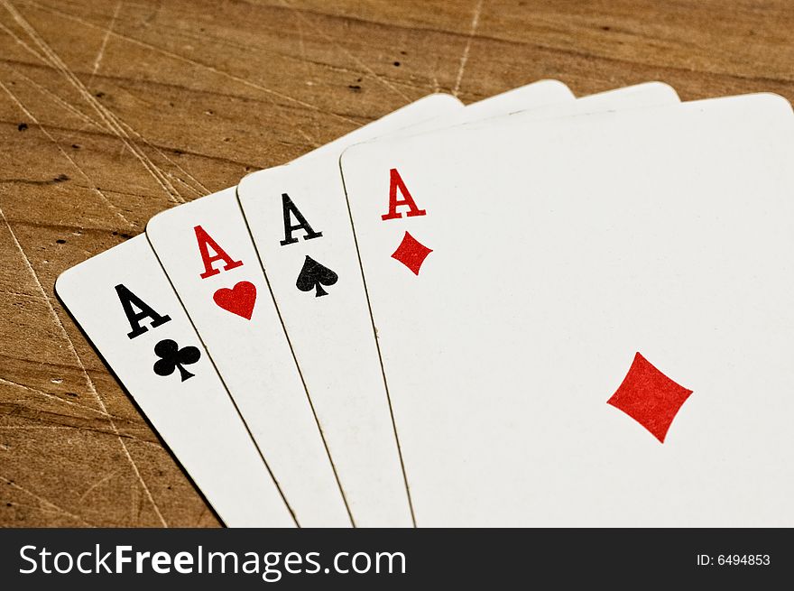 Four aces over an old wooden table, close up.