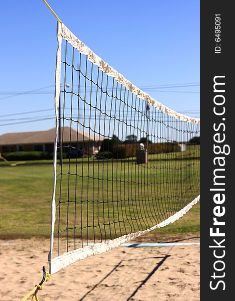 A volleyball net hangs over the sand in the middle of a green city park. A volleyball net hangs over the sand in the middle of a green city park.