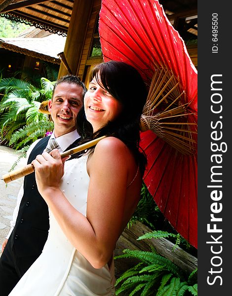 Groom with his bride carrying a red Asian umbrella. Groom with his bride carrying a red Asian umbrella.
