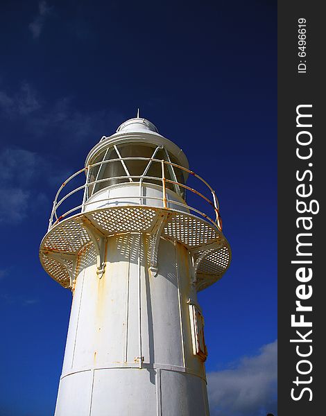 White lighthouse photographed against deep blue summer sky