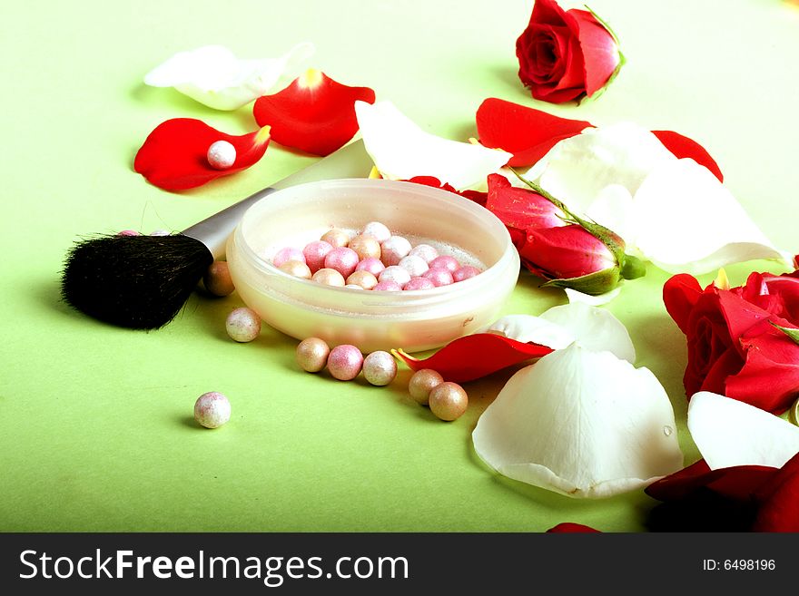 Red and white rose petals and heads with pouder and make-up brush isolated on light background. Red and white rose petals and heads with pouder and make-up brush isolated on light background