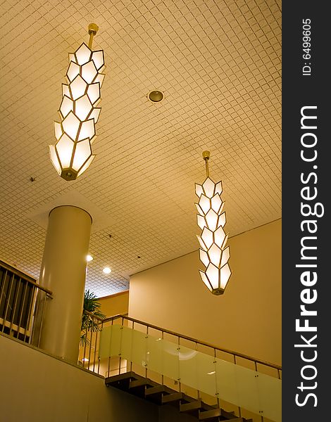 A photograph of a building interior with emphasis on the ceiling lights and stairway