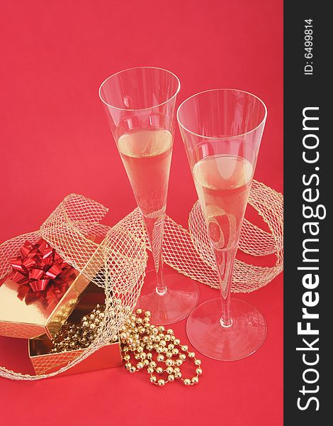 Christmas still life.Christmas present and two glasses of champagne on red background. Christmas still life.Christmas present and two glasses of champagne on red background.