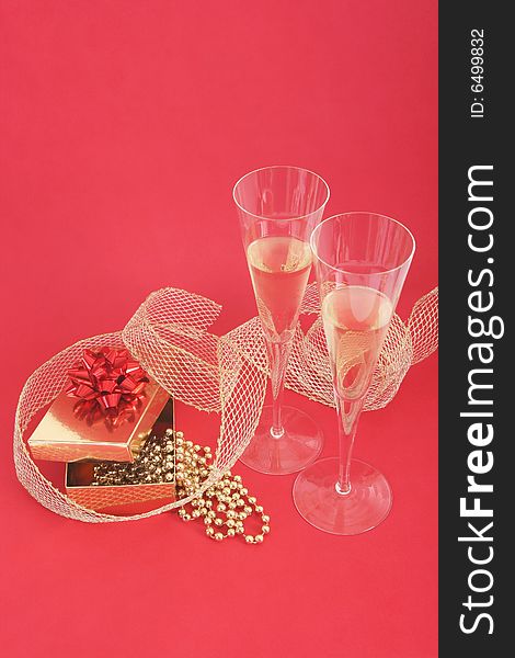 Christmas still life.Christmas present and two glasses of champagne on red background. Christmas still life.Christmas present and two glasses of champagne on red background.