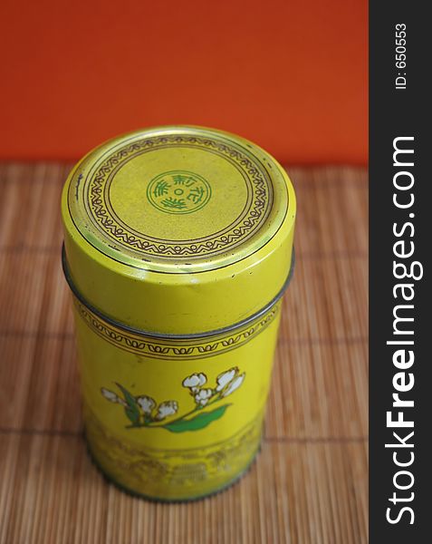 Old Chinese tea tin on bamboo with orange background. Old Chinese tea tin on bamboo with orange background