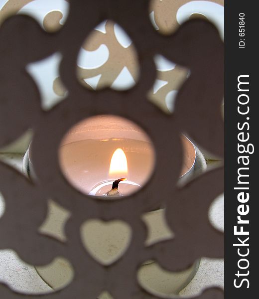 Candle burning in an old holder. (shallow focus on the flame). Candle burning in an old holder. (shallow focus on the flame)