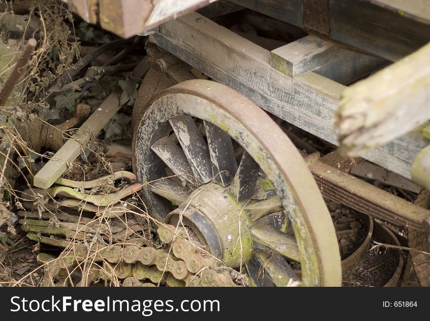 Wheel of old agricultural vehicle, and other remains, rotting in a farm yard. Wheel of old agricultural vehicle, and other remains, rotting in a farm yard.