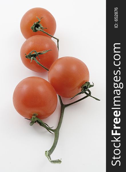 Baby tomatoes on a vine against white background